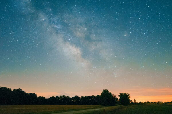 Milchstraße über einer Landschaft bei Nacht, leuchtender Sternenhimmel