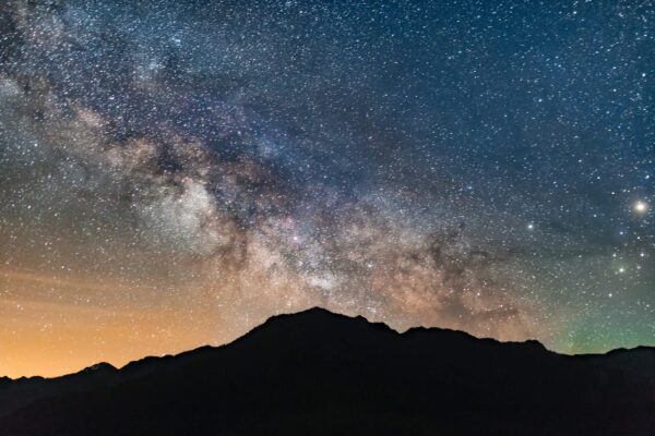 Klarer Sternenhimmel über einer Bergsilhouette, sichtbar ohne Teleskop