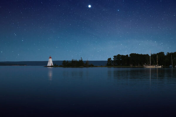 Klarer Sternenhimmel über einem ruhigen See mit Leuchtturm