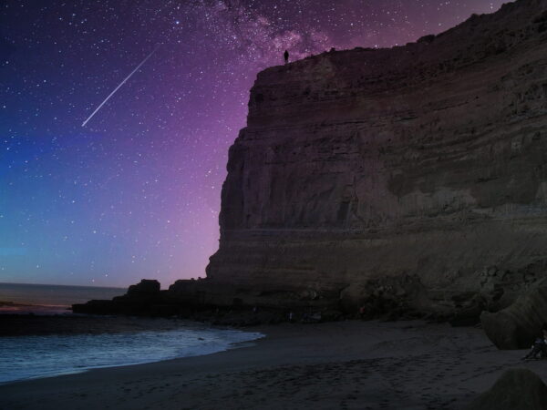 Sternschnuppe über einer Klippe und Strand bei Nacht