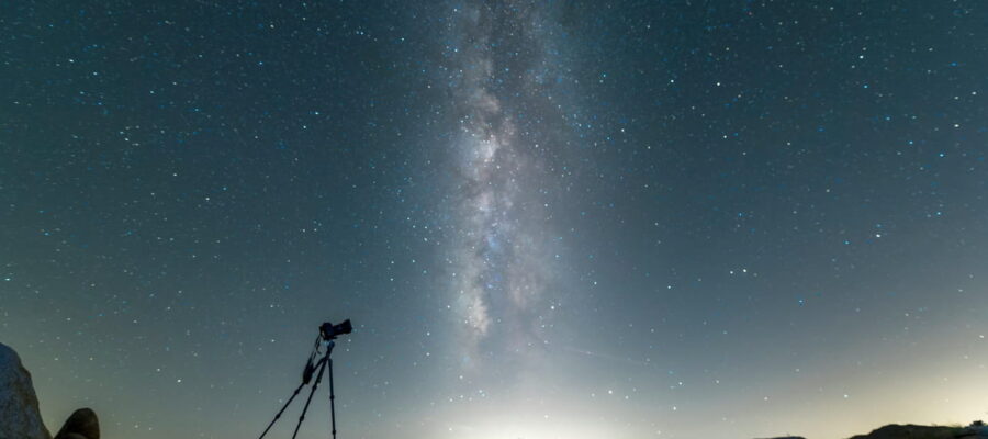 Kamera auf Stativ für Astrofotografie unter sternenklarer Nacht mit der Milchstraße im Hintergrund.